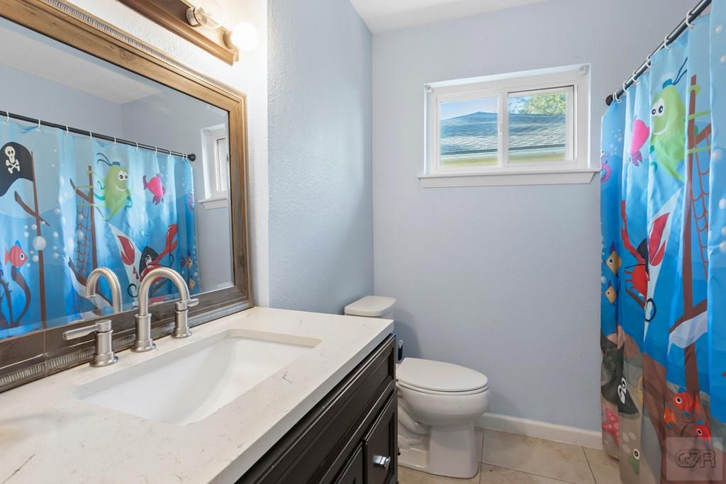 5607 Commodore Drive Dickinson, TX 77539 - Photo 16 of 23 a bathroom with a sink a toilet and shower curtain