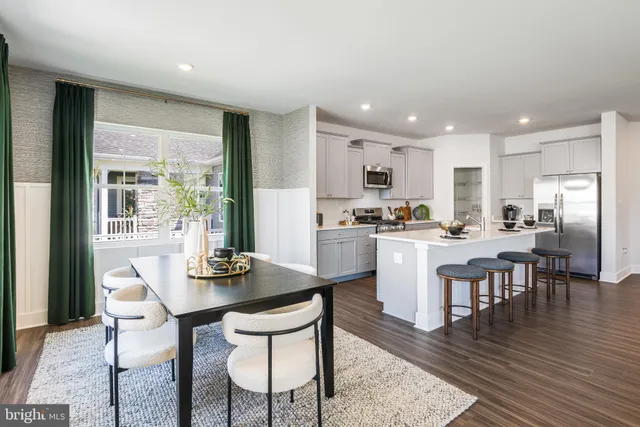 a kitchen with a dining table chairs and refrigerator