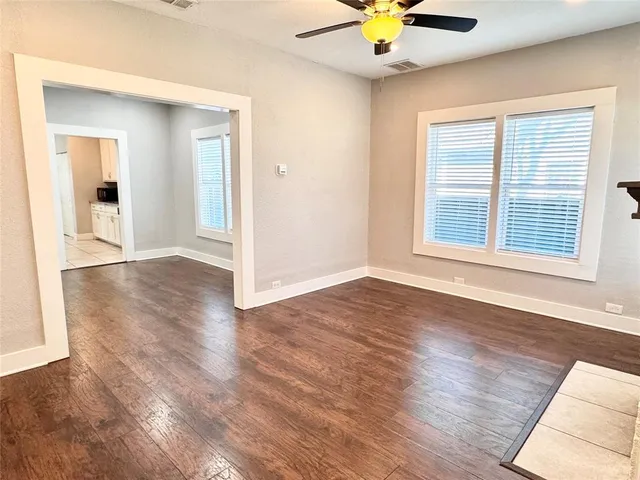 a view of an empty room with window and wooden floor