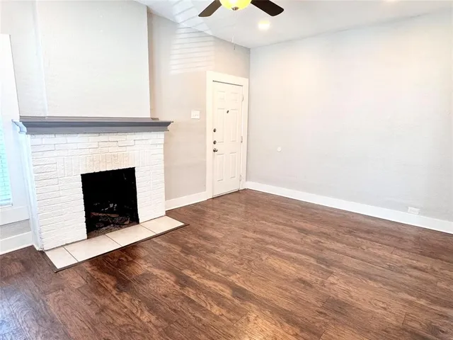 a view of an empty room with wooden floor fireplace and a window