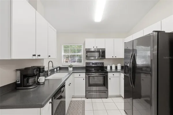 a kitchen with stainless steel appliances granite countertop a sink stove refrigerator and white cabinets