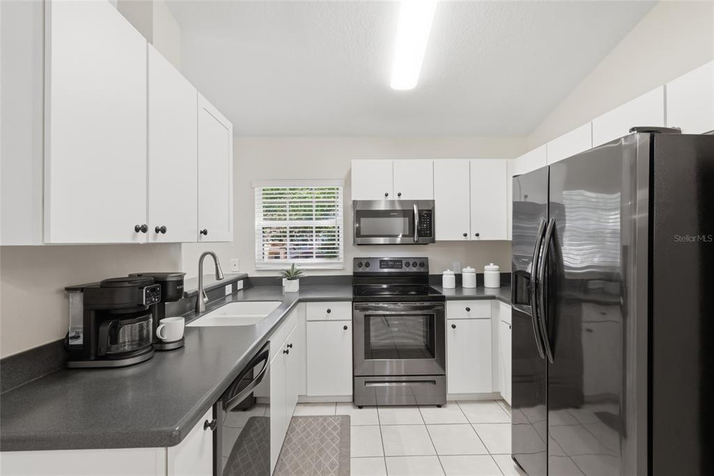 6406 Rosefinch Court, Unit 204 Lakewood Ranch, FL 34202 - Photo 8 of 36 a kitchen with stainless steel appliances granite countertop a sink stove refrigerator and white cabinets