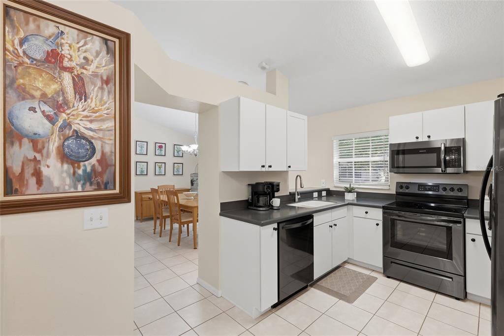 6406 Rosefinch Court, Unit 204 Lakewood Ranch, FL 34202 - Photo 9 of 36 a kitchen with stainless steel appliances granite countertop a stove top oven a sink and dishwasher