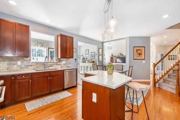 a large kitchen with stainless steel appliances granite countertop a refrigerator a sink dishwasher a dining table and chairs with wooden floor