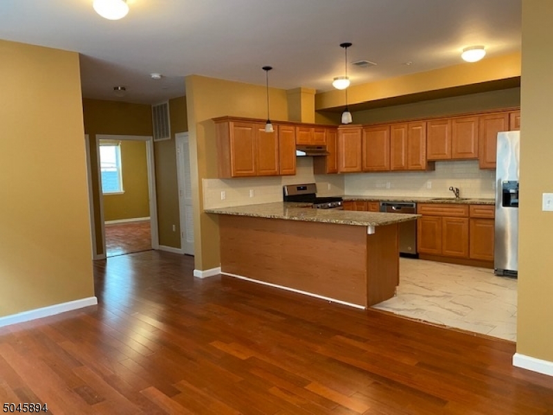a kitchen with stainless steel appliances granite countertop a sink cabinets and wooden floor