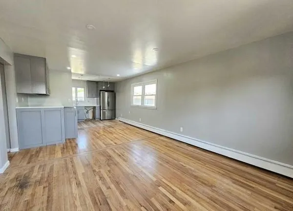 a view of empty room with wooden floor and window