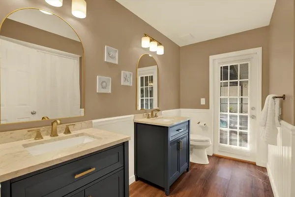 a bathroom with a granite countertop sink mirror and wooden floor