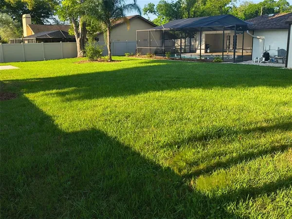 a view of a house with a big yard and large trees