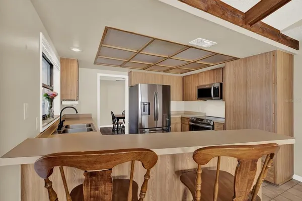 a living room with stainless steel appliances furniture a fireplace and a flat screen tv