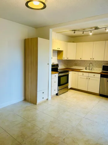 a view of a kitchen with a stove wooden cabinets and a refrigerator