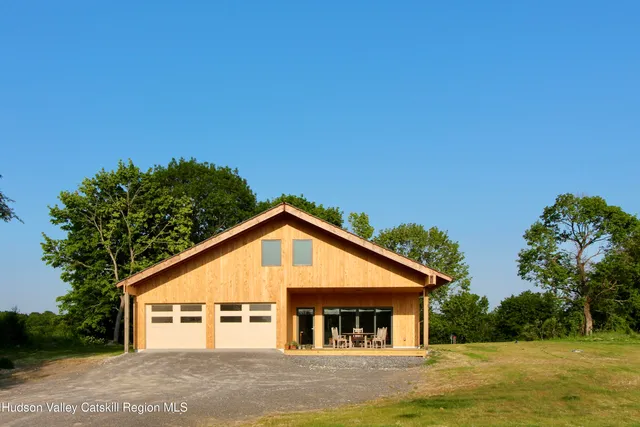 a view of a house with a big yard plants and large tree