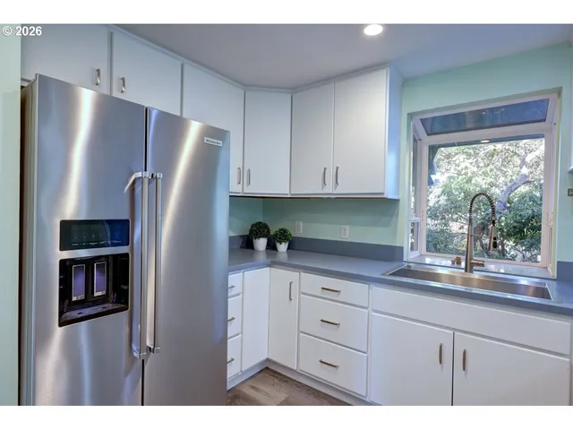 a kitchen with stainless steel appliances granite countertop a refrigerator a sink and a stove