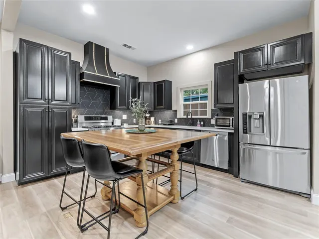 a kitchen with kitchen island granite countertop stainless steel appliances a sink and refrigerator
