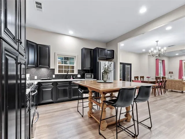 a kitchen with stainless steel appliances granite countertop a stove top oven a sink dishwasher a dining table and chairs with wooden floor