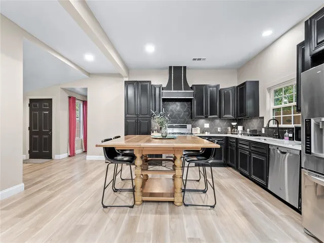 a kitchen with stainless steel appliances a dining table chairs stove microwave and sink
