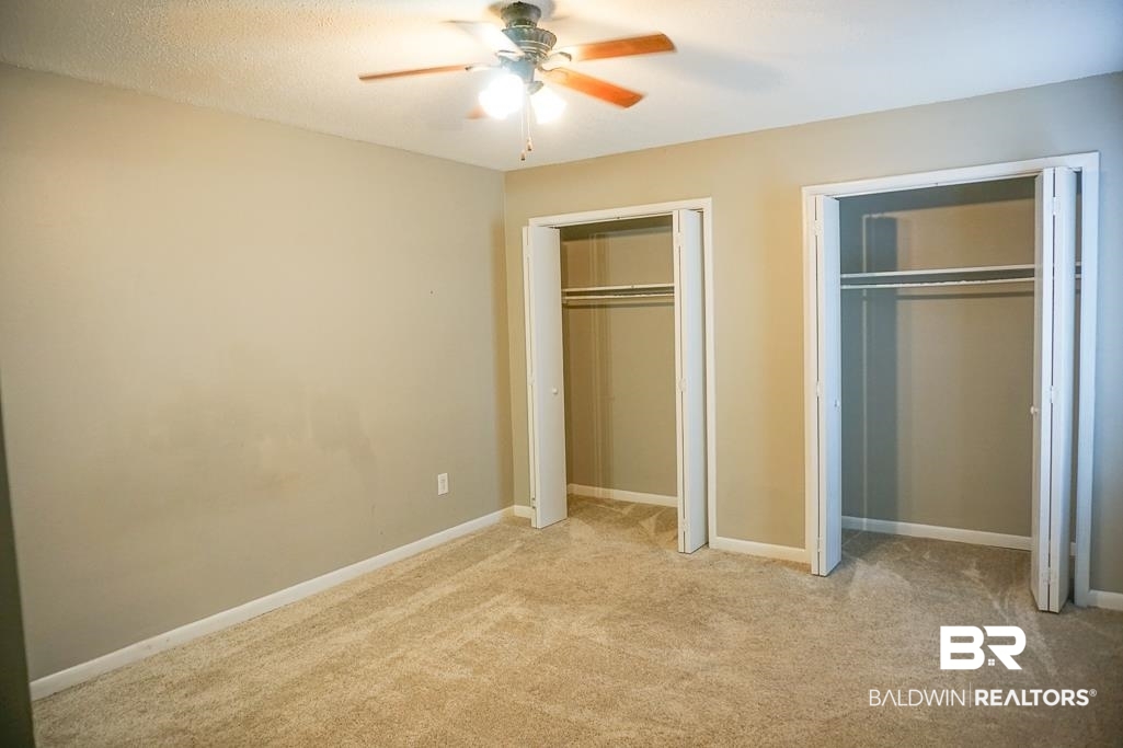 4366 Fathbrook Lane Mobile, AL 36693 - Photo 10 of 14 Unfurnished bedroom with multiple closets, light colored carpet, a ceiling fan, and baseboards