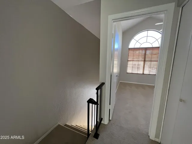 a view of an empty room with wooden floor ceiling fan and windows