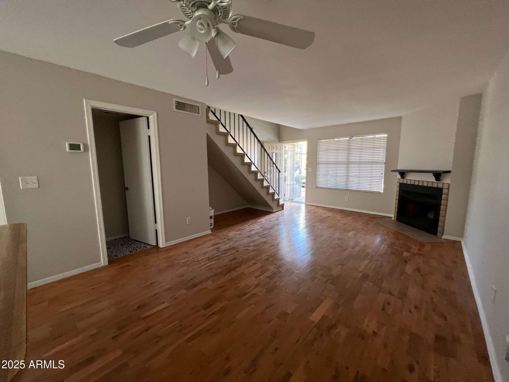 5704 East Aire Libre Avenue, Unit 1081 Scottsdale, AZ 85254 - Photo 8 of 18 a view of an empty room with wooden floor ceiling fan and windows