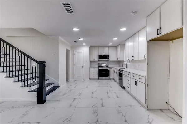 a kitchen with white cabinets stainless steel appliances