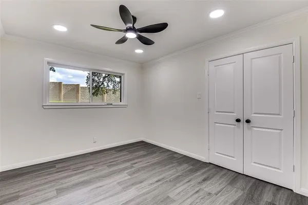 a view of empty room with wooden floor and fan