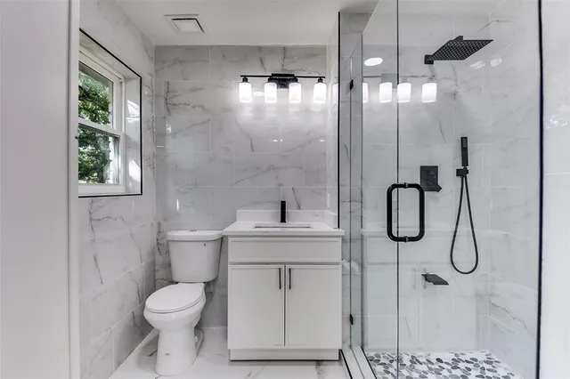 a bathroom with a granite countertop sink a toilet and a shower