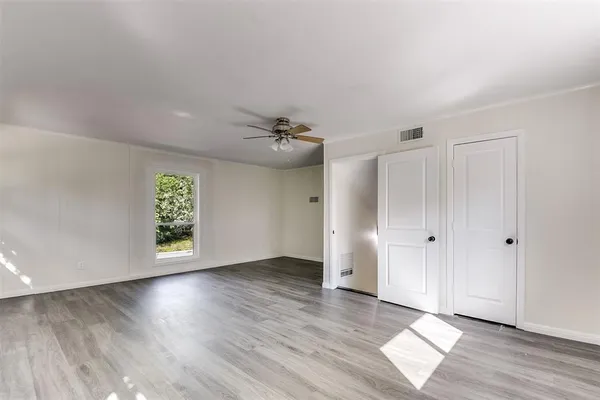 an empty room with wooden floor and windows