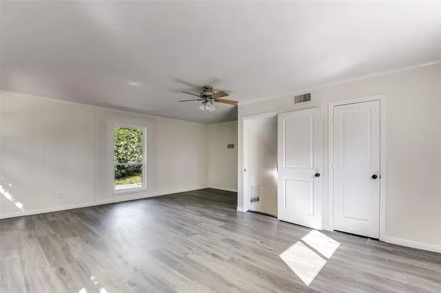 an empty room with wooden floor and windows