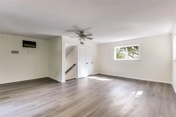a view of an empty room with wooden floor and a window