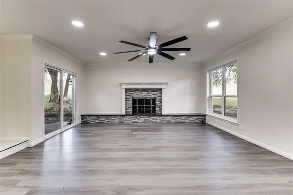 an empty room with wooden floor fireplace and windows