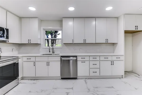 a kitchen with stainless steel appliances granite countertop a stove a sink and a microwave