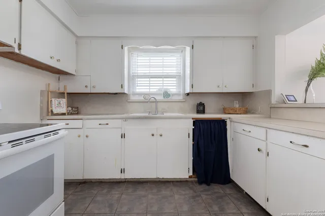 a kitchen with cabinets appliances a sink and a window