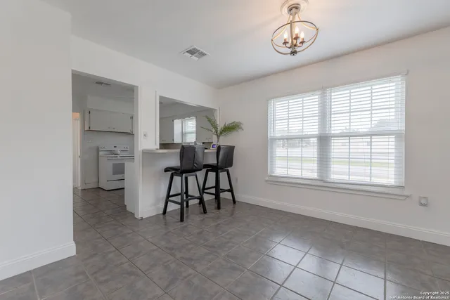 an empty room with chandelier fan and windows