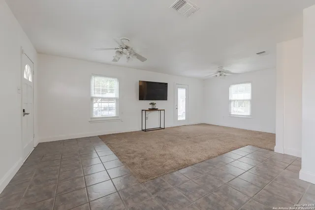 a view of an empty room with a window and a kitchen