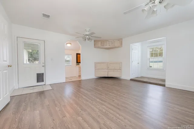 an empty room with wooden floor chandelier and windows