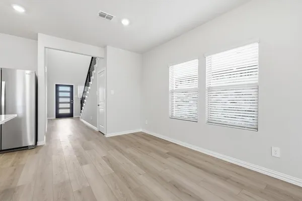 a view of an empty room with a window and wooden floor