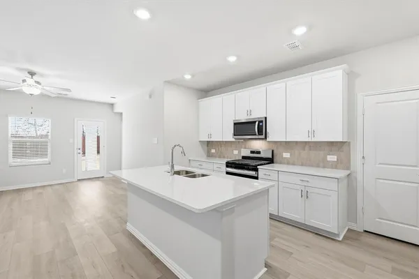 a kitchen with sink a microwave and cabinets