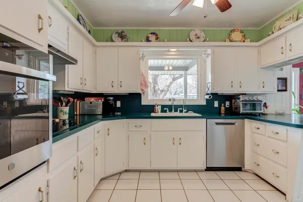 a kitchen with white cabinets a sink and appliances