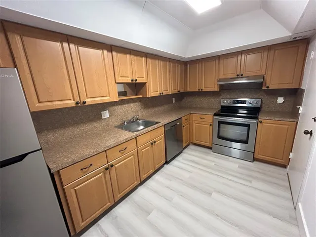 a kitchen with stainless steel appliances granite countertop a stove a sink and a refrigerator