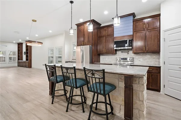 a kitchen with stainless steel appliances kitchen island granite countertop a kitchen island a stove a dining table and chairs
