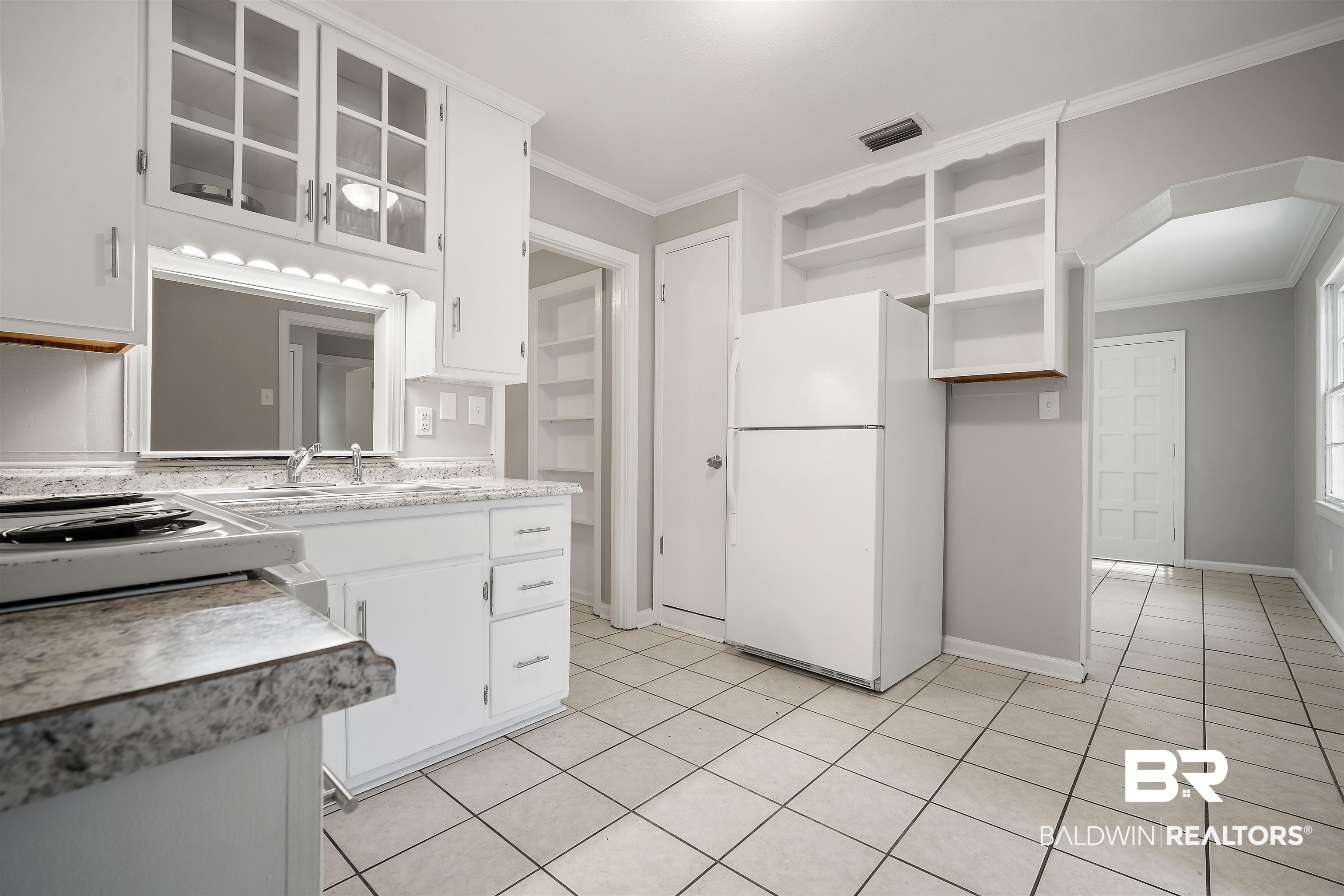 963 Shady Brook Drive Mobile, AL 36606 - Photo 8 of 20 Kitchen featuring freestanding refrigerator, light tile patterned flooring, open shelves, arched walkways, and ornamental molding