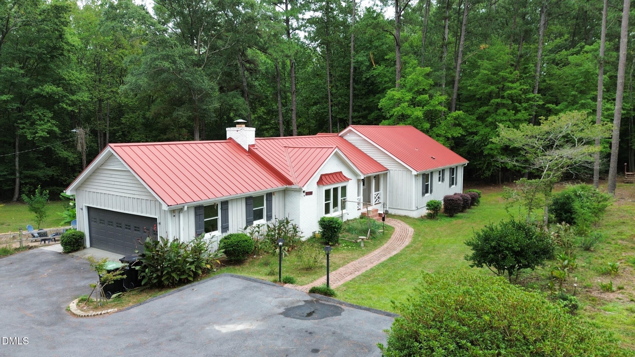 2329 Win Road Garner, NC 27529 - Photo 81 of 90 White siding exterior with a red metal roof, attached two-car garage, and a brick-finish pathway