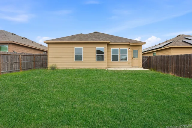 a view of a house with a yard plants and large tree