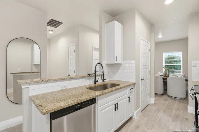 a kitchen with granite countertop a sink and white cabinets