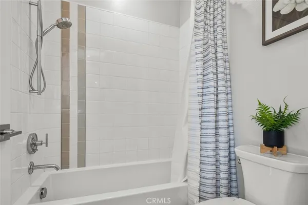 a bathroom with a shower curtain a potted plant and a shower