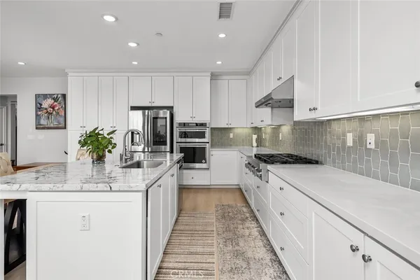 a kitchen with granite countertop a sink stainless steel appliances and white cabinets