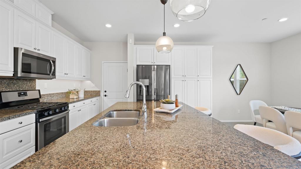 21578 Saddle Bred Lane Escondido, CA 92029 - Photo 10 of 49 a large kitchen with granite countertop a stove a sink a dining table and chairs