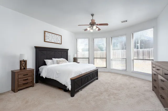 a spacious bedroom with a bed a couch and a large window