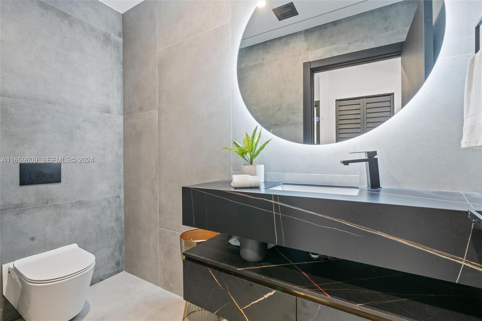 2261 Northeast 192 Street Miami, FL 33180 - Photo 14 of 24 a bathroom with a sink a toilet and mirror