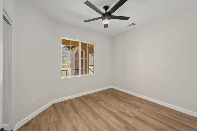 an empty room with a window and ceiling fan