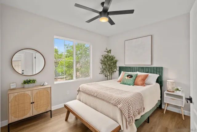 a bedroom with a bed a mirror on dresser and a window